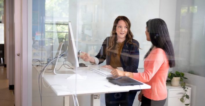 Two women at standing desk working